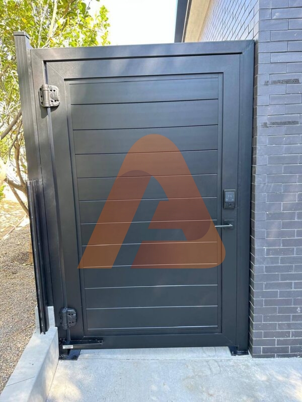 Real installed black full-privacy aluminum pedestrian gate with lock, hinge post and concrete walkway