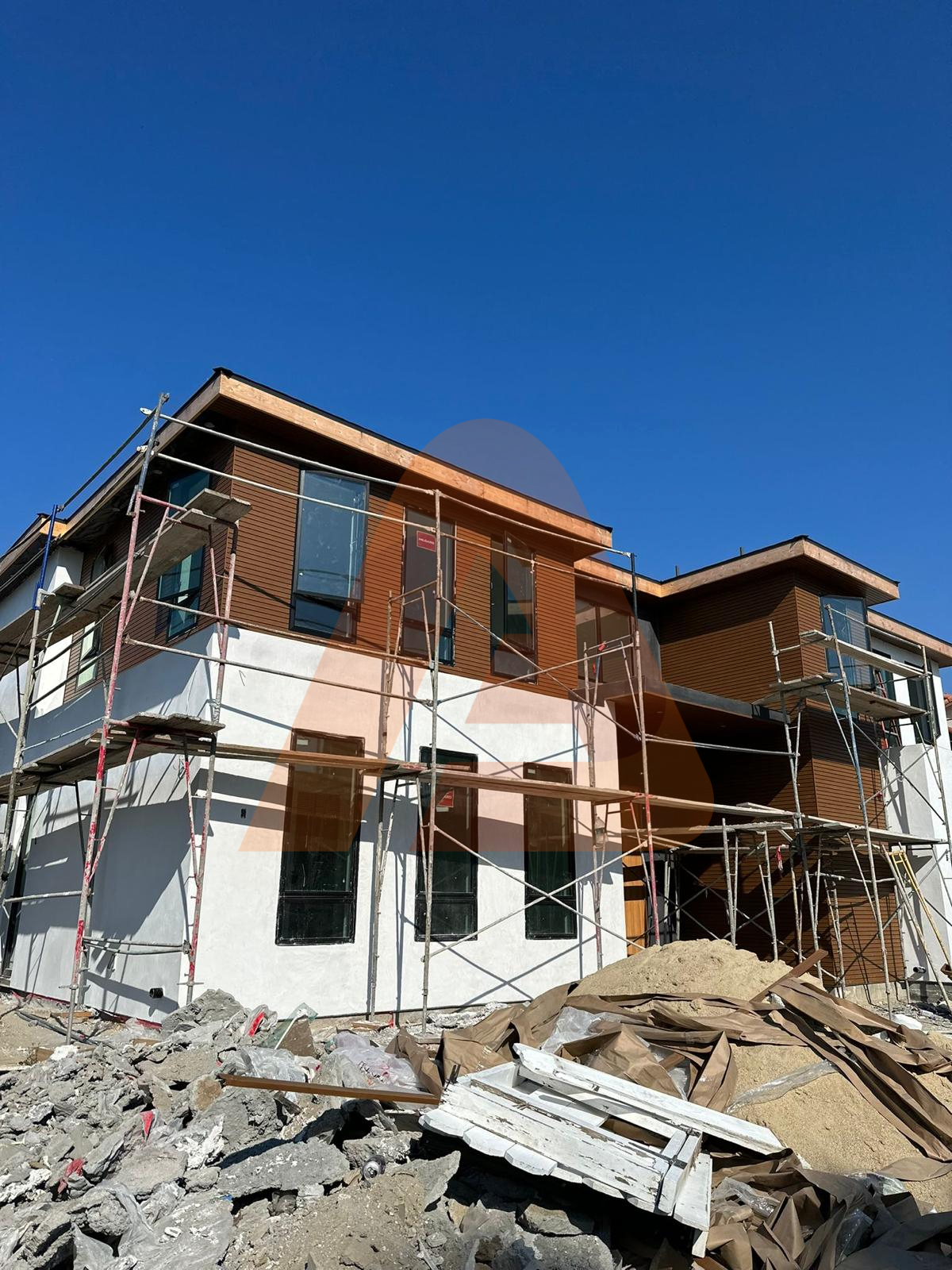 Real multi-story construction project with wood-look aluminum cladding installed around windows on several exterior elevations